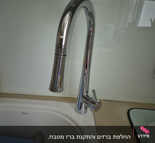 ברז נירוסטה מעל כיור מטבח עם כלים